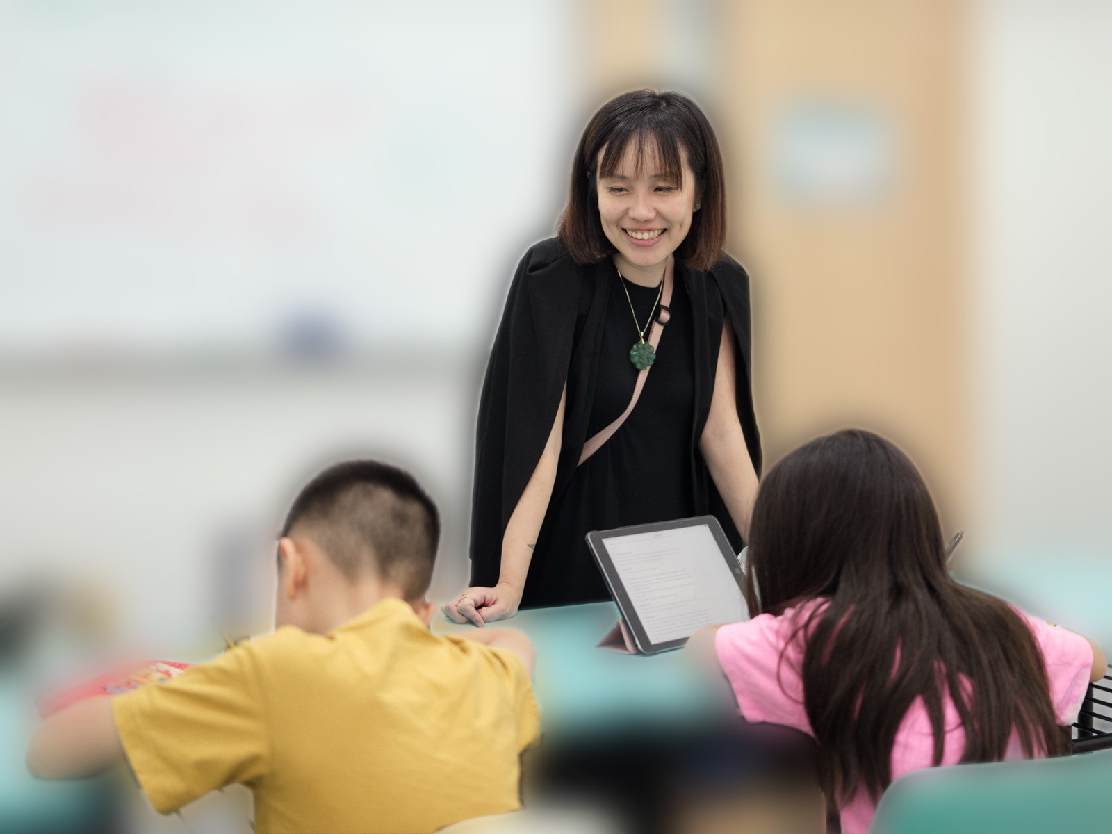 Ms Eileen Tan teaching two students at their desks in the TLA classroom