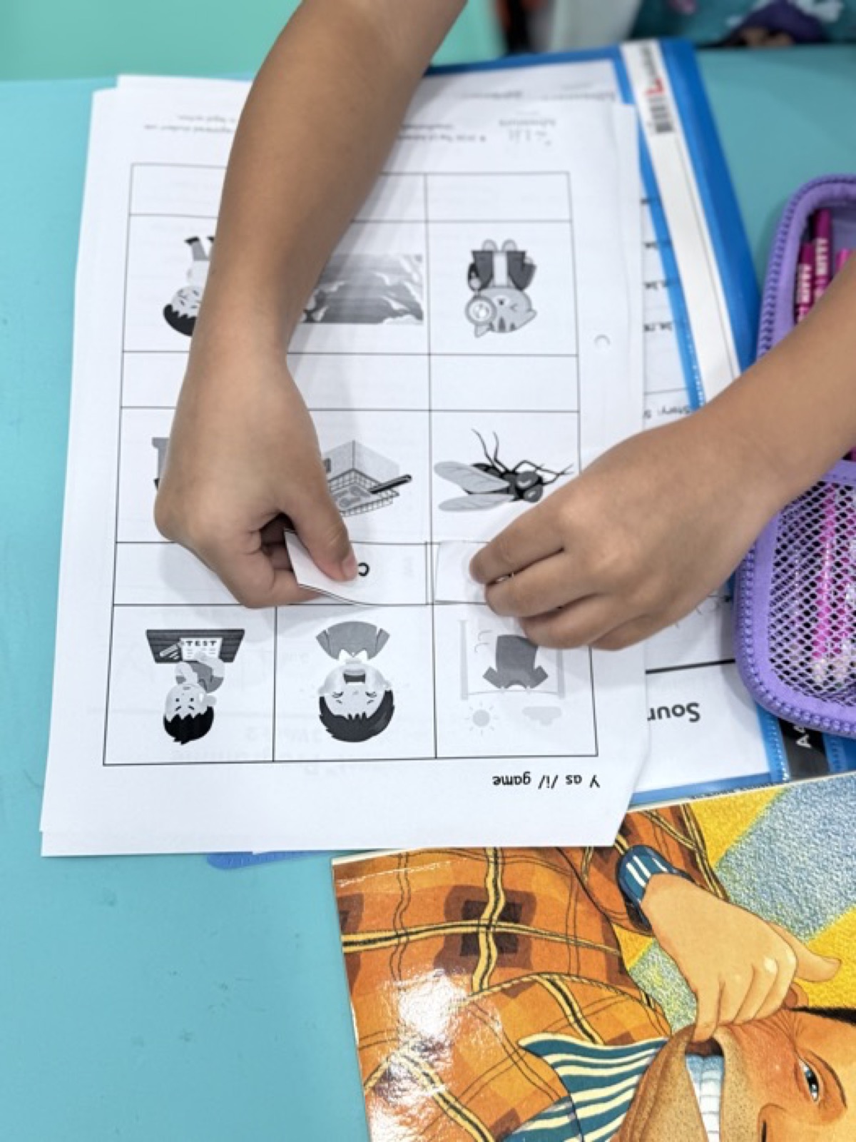 Student's hands working through a phonics sound-matching game