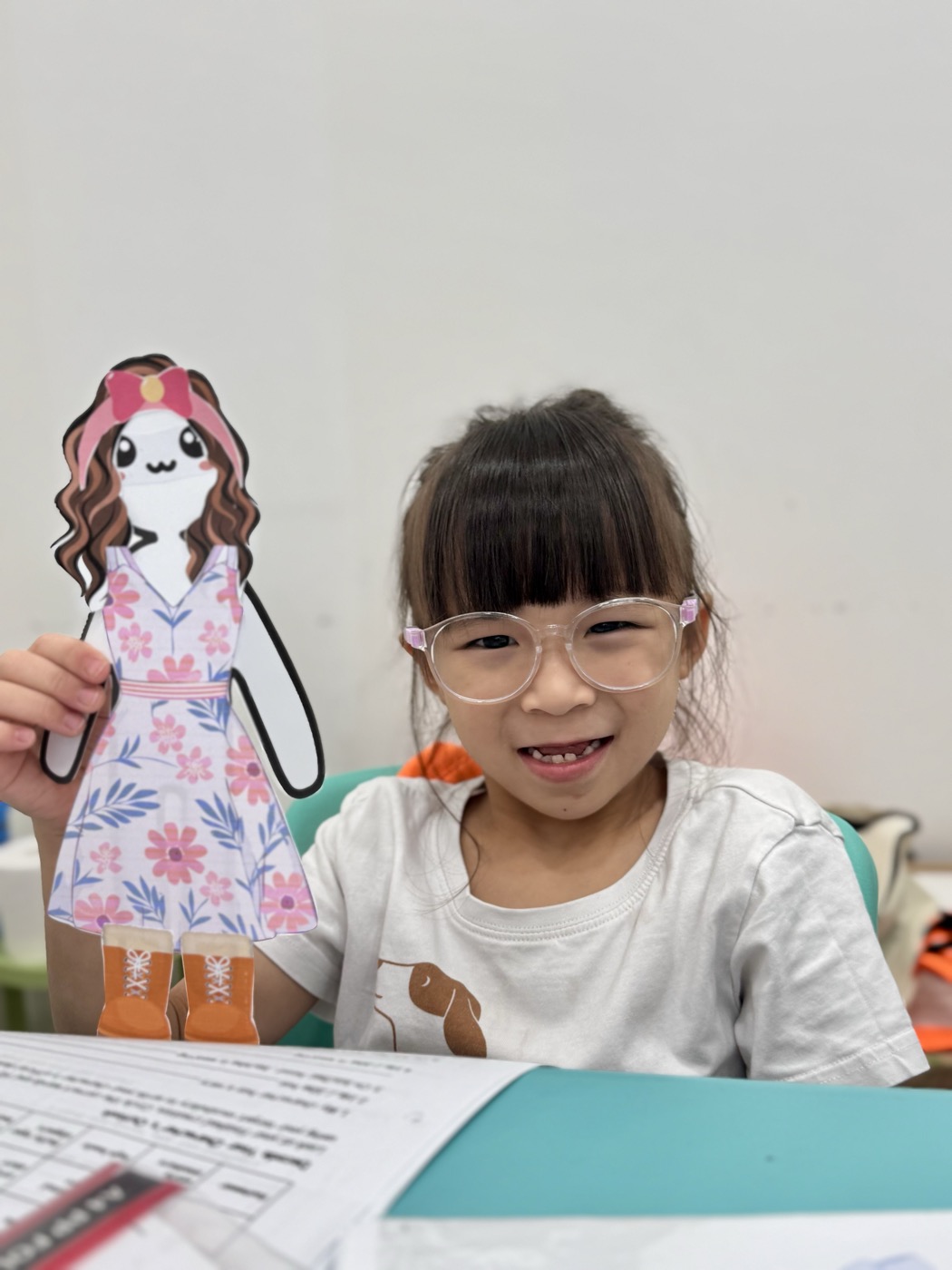 Student holding her handmade paper-doll character, a creative writing craft activity