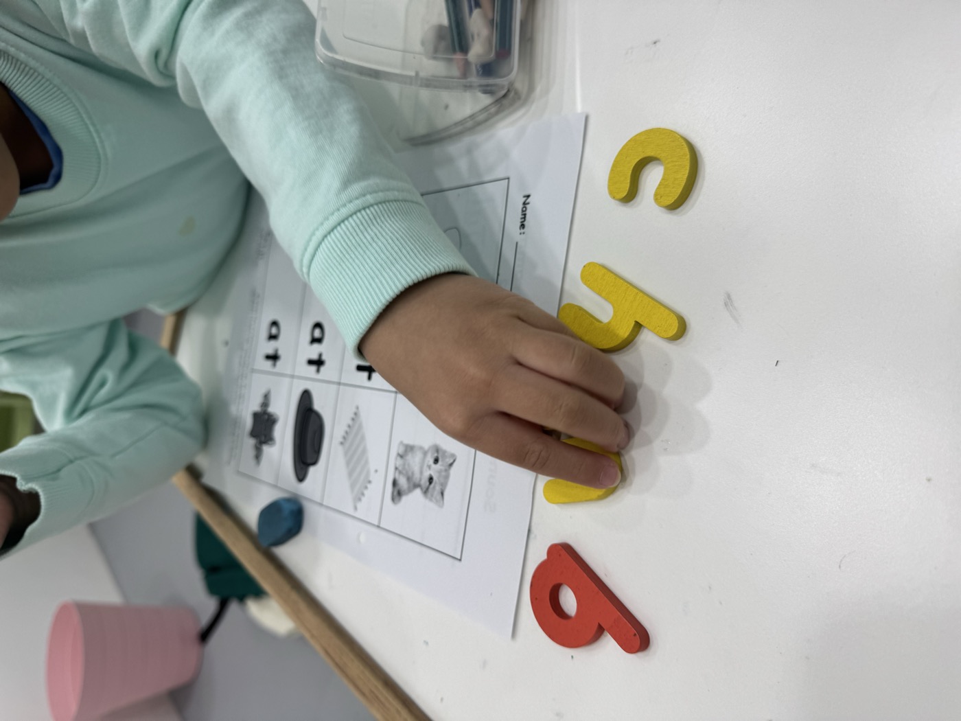 A Lit Adventure teacher's hand guiding a student through a letter activity