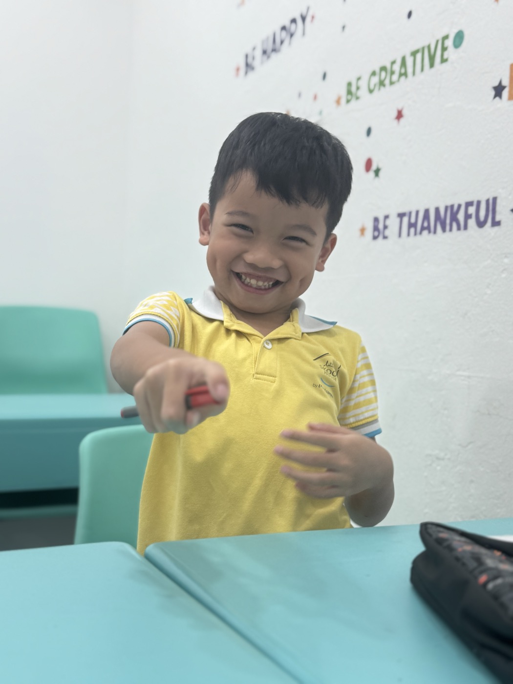 Student smiling brightly in front of the classroom wall